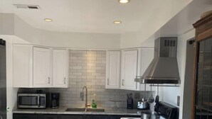 Una cocina moderna con armarios blancos, una campana extractora de acero inoxidable y un horno empotrado.