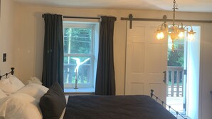 Un dormitorio con cama, una ventana con cortinas, una puerta y una araña.