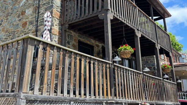 Un edificio de piedra con un balcón de madera y cestas de flores colgantes.