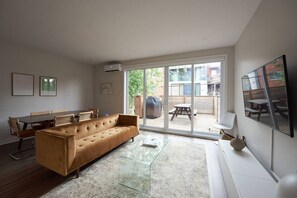Ein modernes Wohnzimmer mit einer Couch, einem Esstisch, Stühlen und einer Schiebetür zu einer Außenpatio.