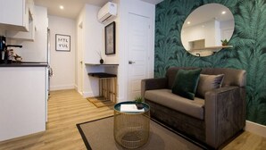 Un soggiorno moderno con un divano, uno specchio rotondo e una parete decorata con un motivo verde.