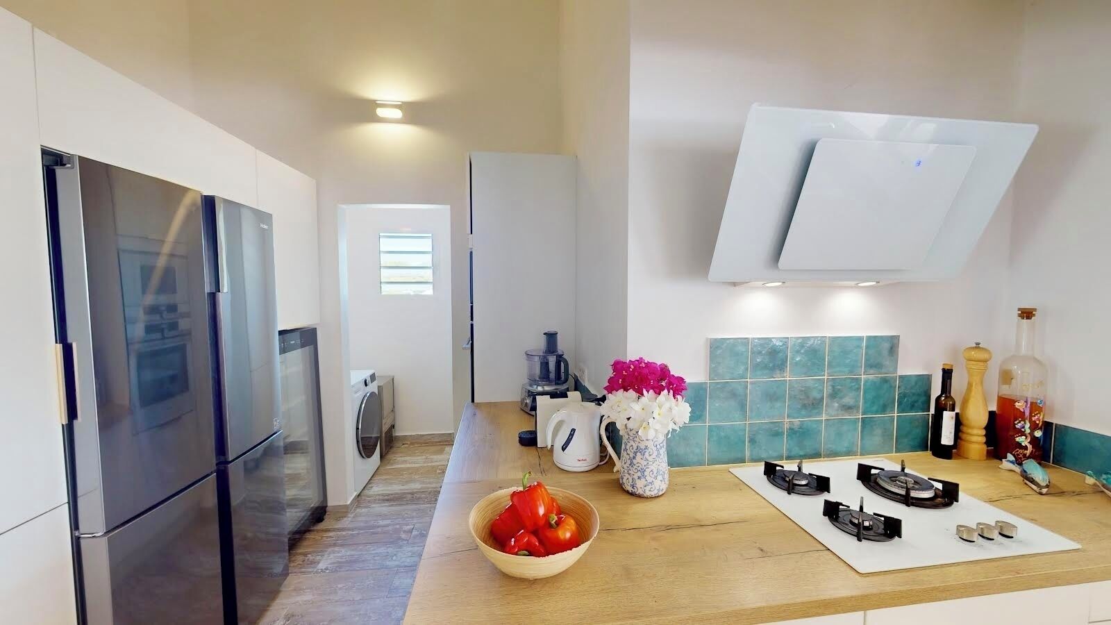 A modern kitchen with stainless steel appliances, a wooden countertop, and a backsplash.