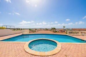 A swimming pool with a hot tub, surrounded by a brick patio and a white railing. - Villa with private pool with endless views. January 2027 availability! (Noord)