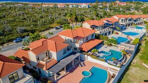 Un resort con varias edificaciones, una piscina y una carretera al fondo.