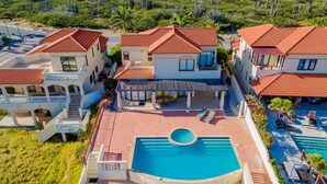 Un edificio grande de varios pisos con piscina, asientos al aire libre y un porche cubierto.