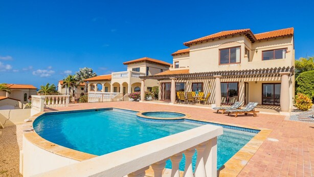 Un resort con una amplia piscina, varias villas y un jardín bien cuidado.