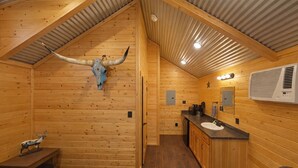 A log cabin interior with a wooden ceiling, a mounted animal skull, a sink, and a bench. - Beautiful Log cabin overlooking a meadow (Pipe Creek)