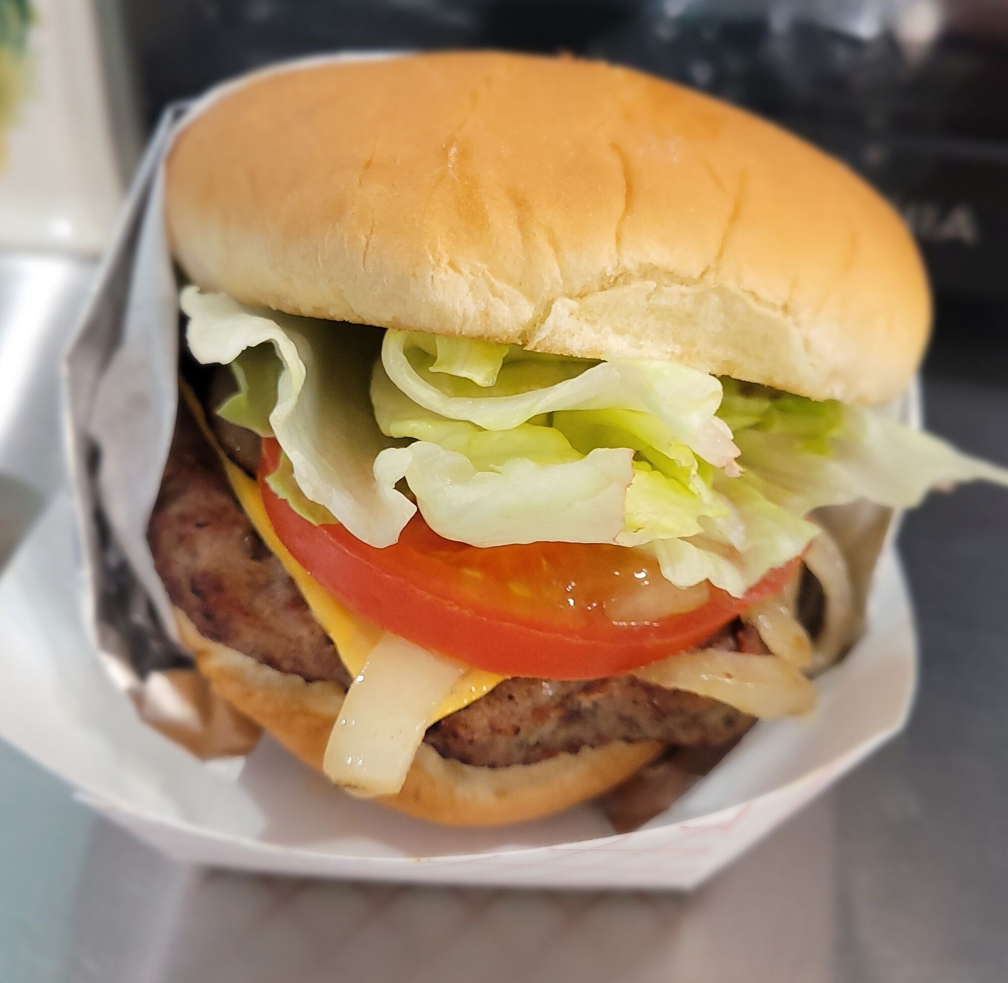 Un hamburger composé d’un pain, de laitue, de tomate, de fromage et d’une galette de viande.