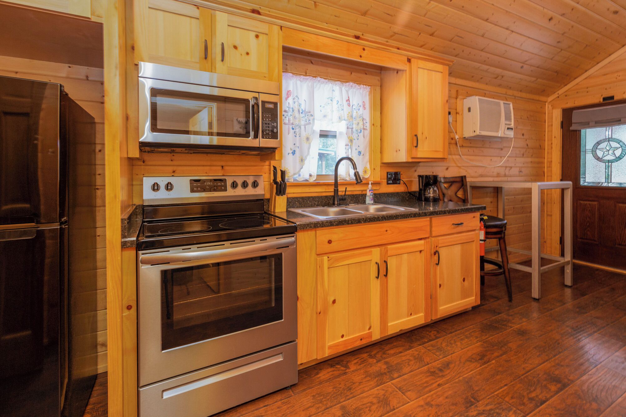 A kitchen with wooden cabinets, a stainless steel stove, a microwave, and a sink.