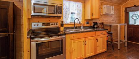 A kitchen with wooden cabinets, a stainless steel stove, a microwave, and a sink.