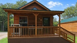 Eine Holzhütte mit überdachter Veranda, einer Tür und einem Fenster.