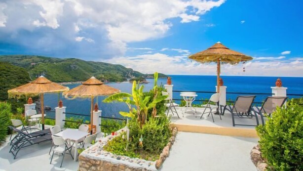 Un área de estar al aire libre con sombrillas, sillas y vista al mar.