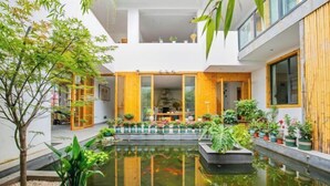 Un edificio moderno con un patio, un estanque y plantas en macetas.