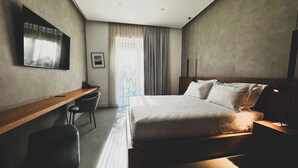 A modern hotel room with a large bed, a desk, and a chair. - J Maluni City Hotel (Rome)