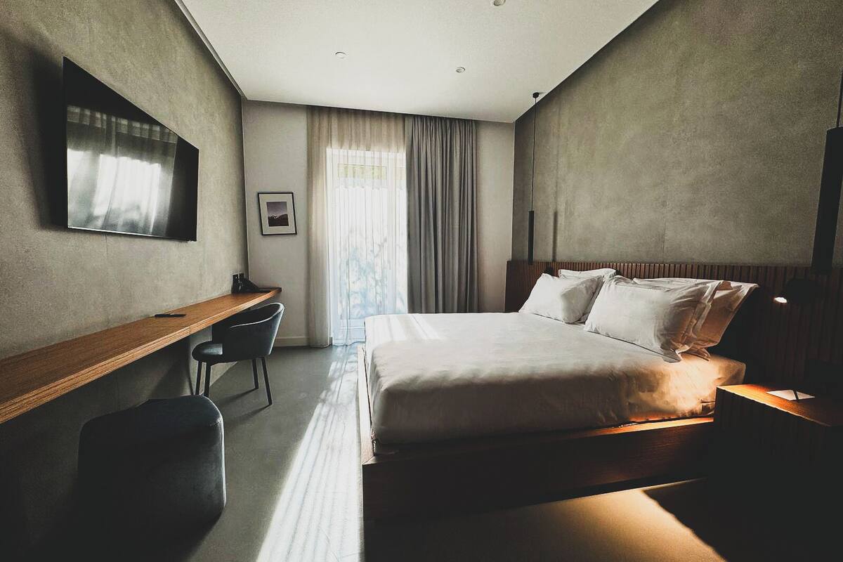 Una habitació d'hotel moderna amb un llit gran, un escriptori i una cadira.