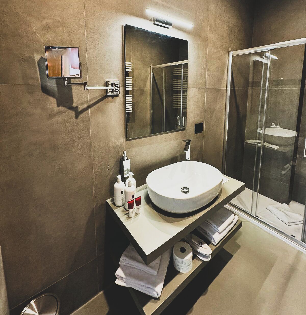 A modern bathroom with a round sink, a mirror, and a glass shower enclosure.