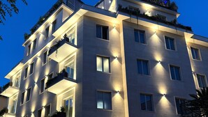 A multi-story hotel with balconies, large windows, and a gated entrance. - J Maluni City Hotel (Rome)