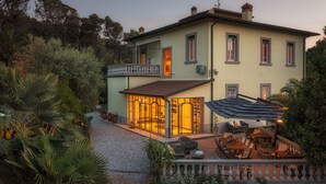 A two-story house with a covered patio, outdoor seating, and a garden. - Villa Gaius 8+2, Emma Villas (Rosignano Marittimo)