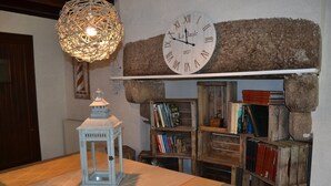 A room with a large wall clock, a wooden bookshelf, and a white lantern on a table.