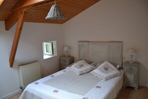 Une chambre à coucher avec un lit, deux tables de chevet, une fenêtre et un radiateur.