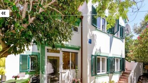 A two-story building with green shutters, a patio with outdoor seating, and a potted plant. - Apartments Carpe Diem (Vir)