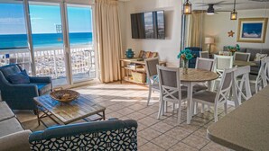 A spacious living area with a balcony overlooking the beach, furnished with a sofa, chairs, and a coffee table. - Pelican Beach 0206 1 Bedroom Condo by Pelican Beach Management (Destin)