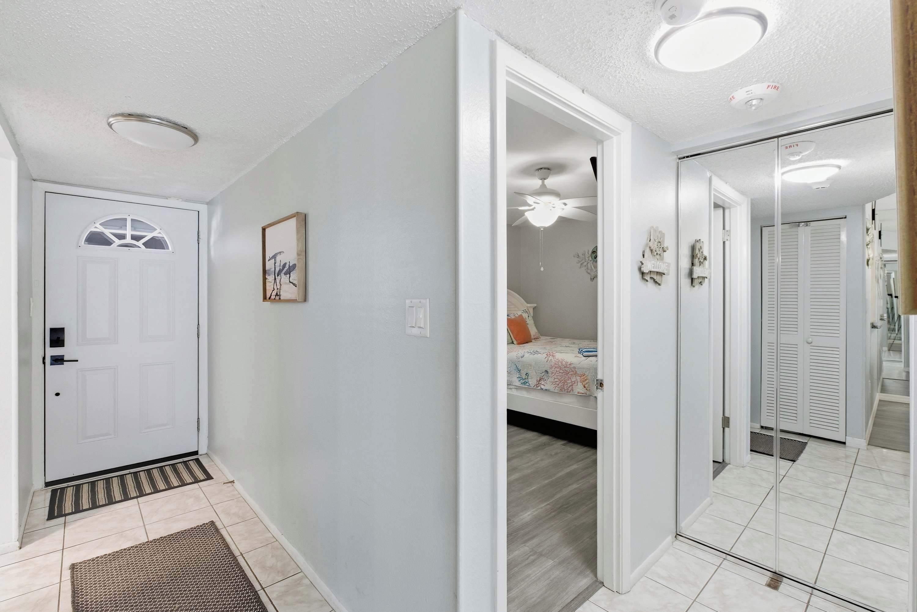 A hallway with a white door, a small rug, and a ceiling light.