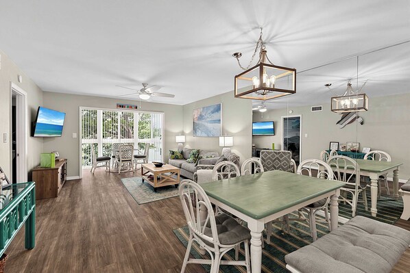 A spacious living area with a dining table, chairs, a sofa, and a television.