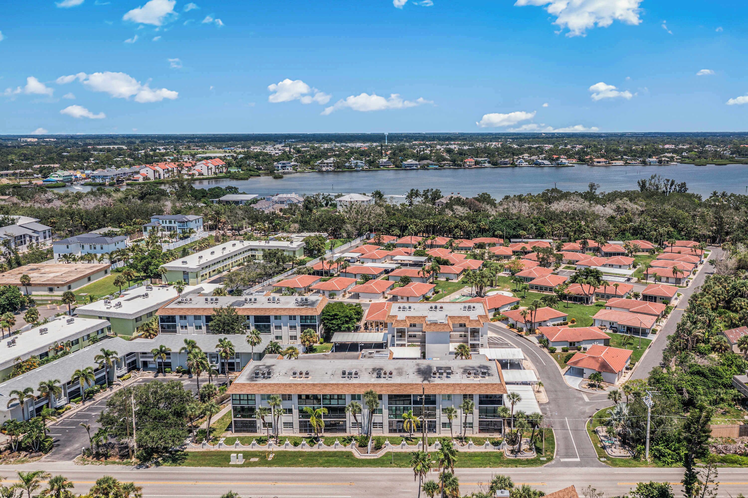A residential area with a large building complex, a lake, and a bridge in the background.