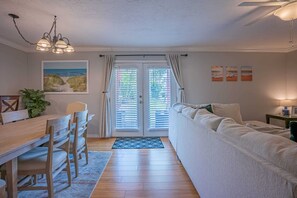 Un salon chaleureux avec une table à manger en bois, des chaises, un canapé et un ventilateur de plafond.