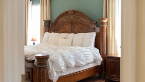 A wooden bed with a headboard, white bedding, and curtains.