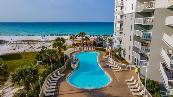 Guests can enjoy the ocean view from their balcony or relax by the central pool surrounded by lounge chairs.