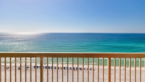 A beach view from a balcony with a railing, clear sky, and calm sea. - Pelican Beach 1406 1 Bedroom Condo by Pelican Beach Management (Destin)