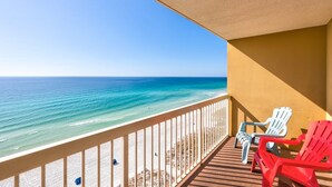 A balcony with a view of the ocean, featuring a wooden deck and two red chairs. - Pelican Beach 1406 1 Bedroom Condo by Pelican Beach Management (Destin)
