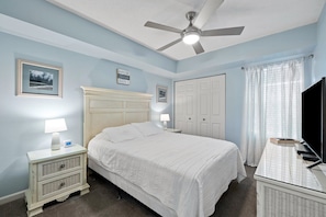 A bedroom with a bed, bedside tables, a ceiling fan, a TV, and a wardrobe.