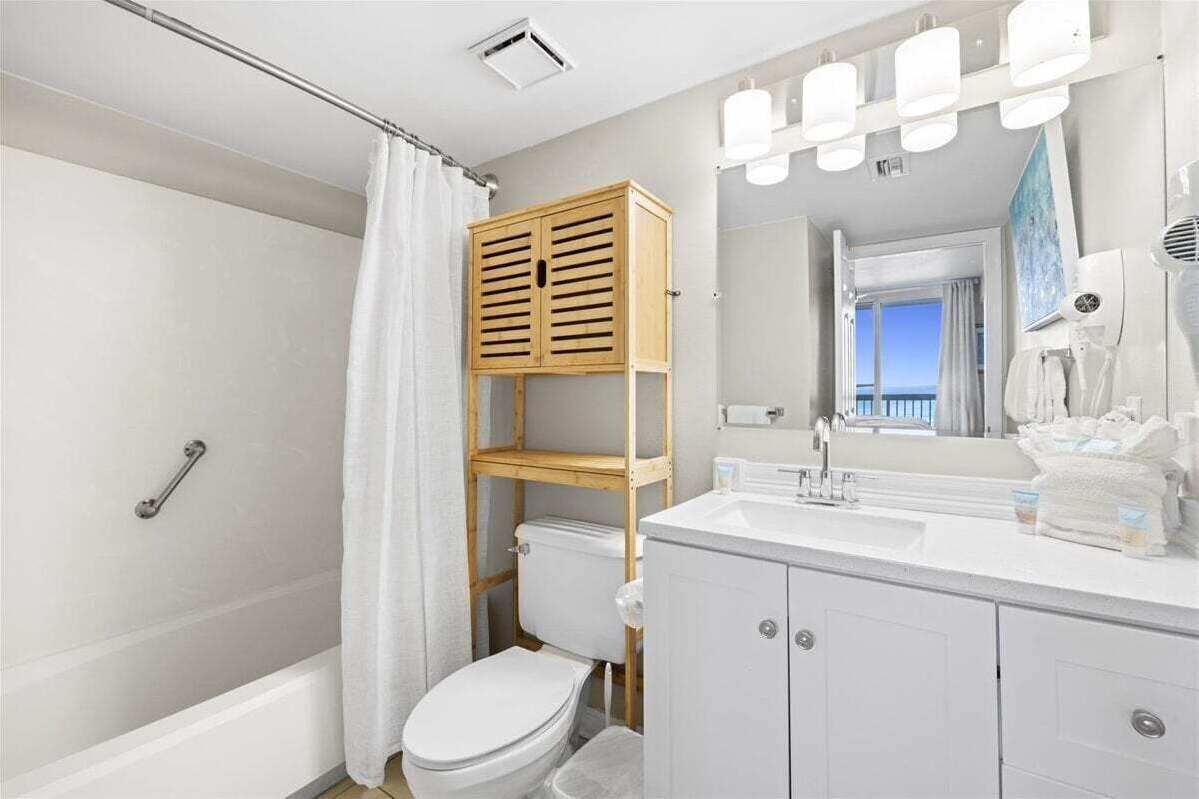 Ein Badezimmer mit Dusche, Toilette, Waschtisch und einer Holzregaleinrichtung.
