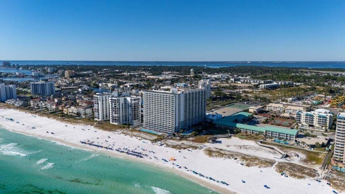 A coastal cityscape with high-rise buildings, a beach, and a marina.