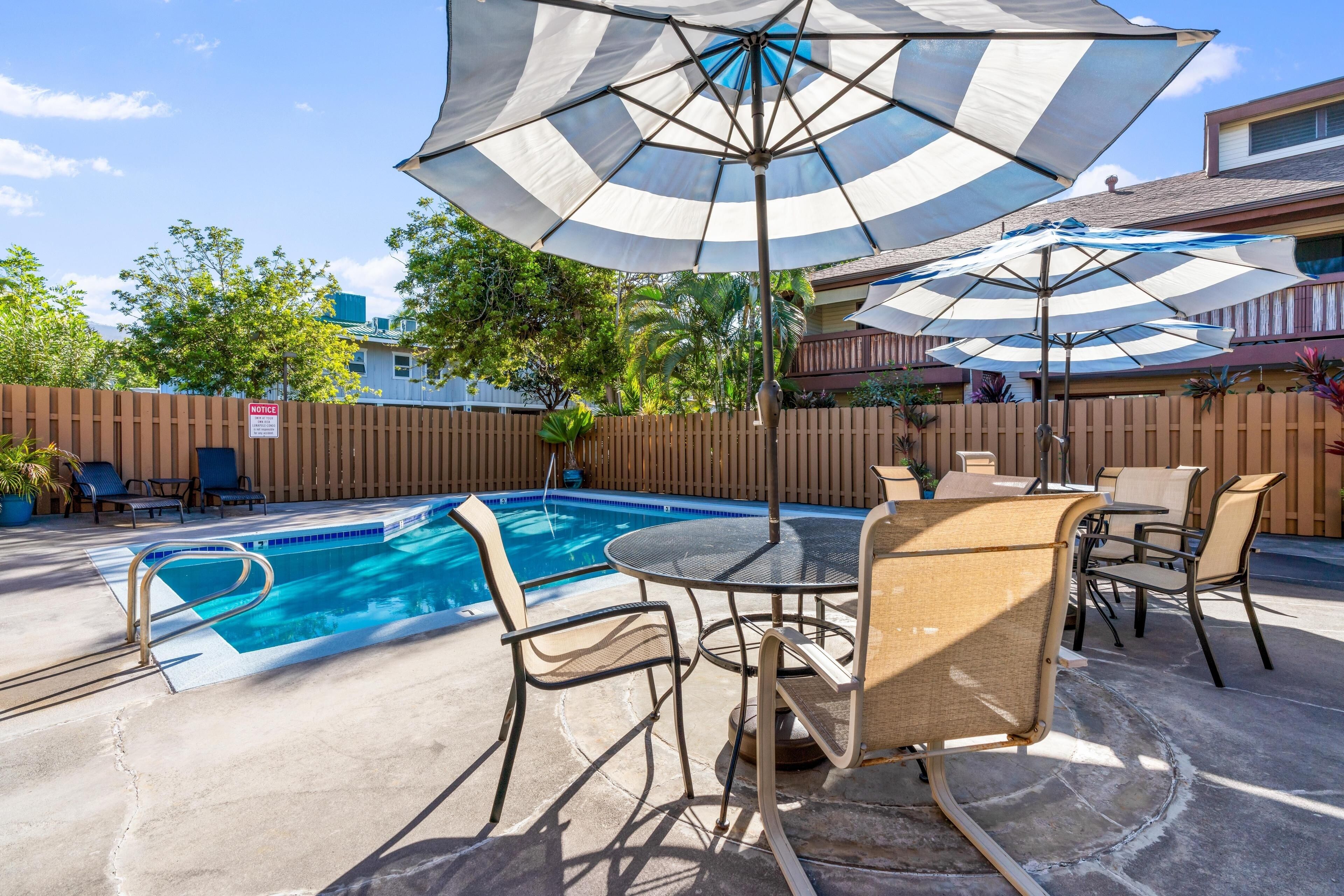 A pool area with a table and chairs, surrounded by a wooden fence.