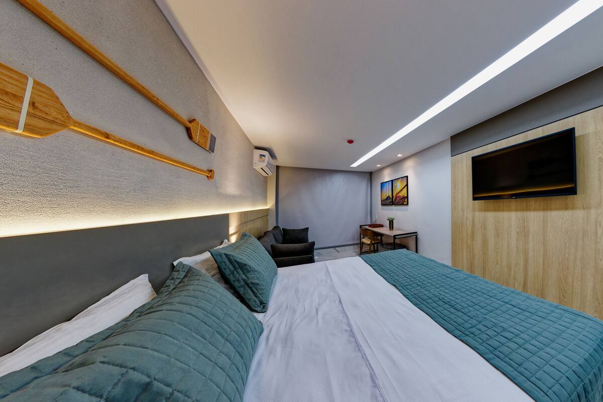 A modern hotel room with a large bed, a desk, and a TV mounted on the wall.