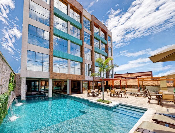 Un hotel moderno con piscina, mobiliario exterior y vistas al cielo.