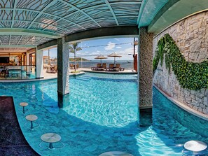 Una piscina con agua cristalina azul, sillas de descanso y vista al mar.