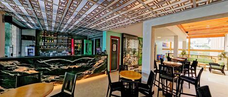 A modern bar area with a marble counter, multiple seating options, and a patterned ceiling.