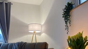A modern living room with a grey sofa, a wooden coffee table, a floor lamp, and a vase with yellow flowers.