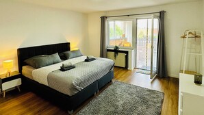 A bedroom with a bed, bedside tables, a window, and a view of the outdoors.