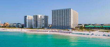 A beachfront hotel with multiple high-rise buildings, a sandy beach, and clear turquoise waters.
