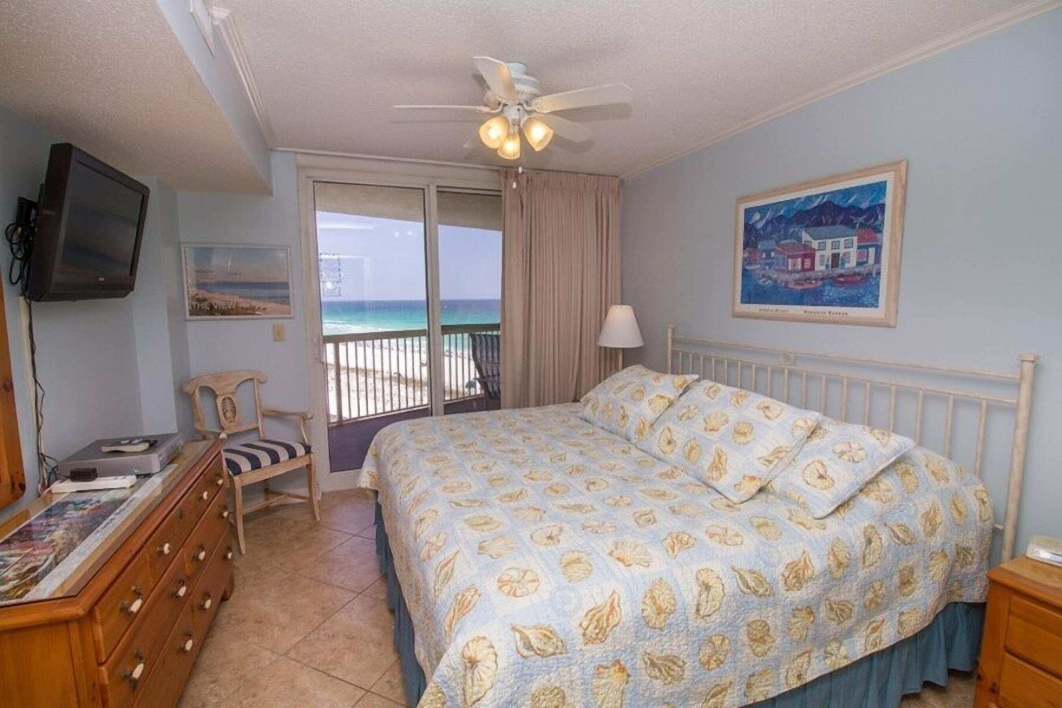 Une chambre à coucher comprenant un lit, une télévision, une chaise, une commode et un tableau.