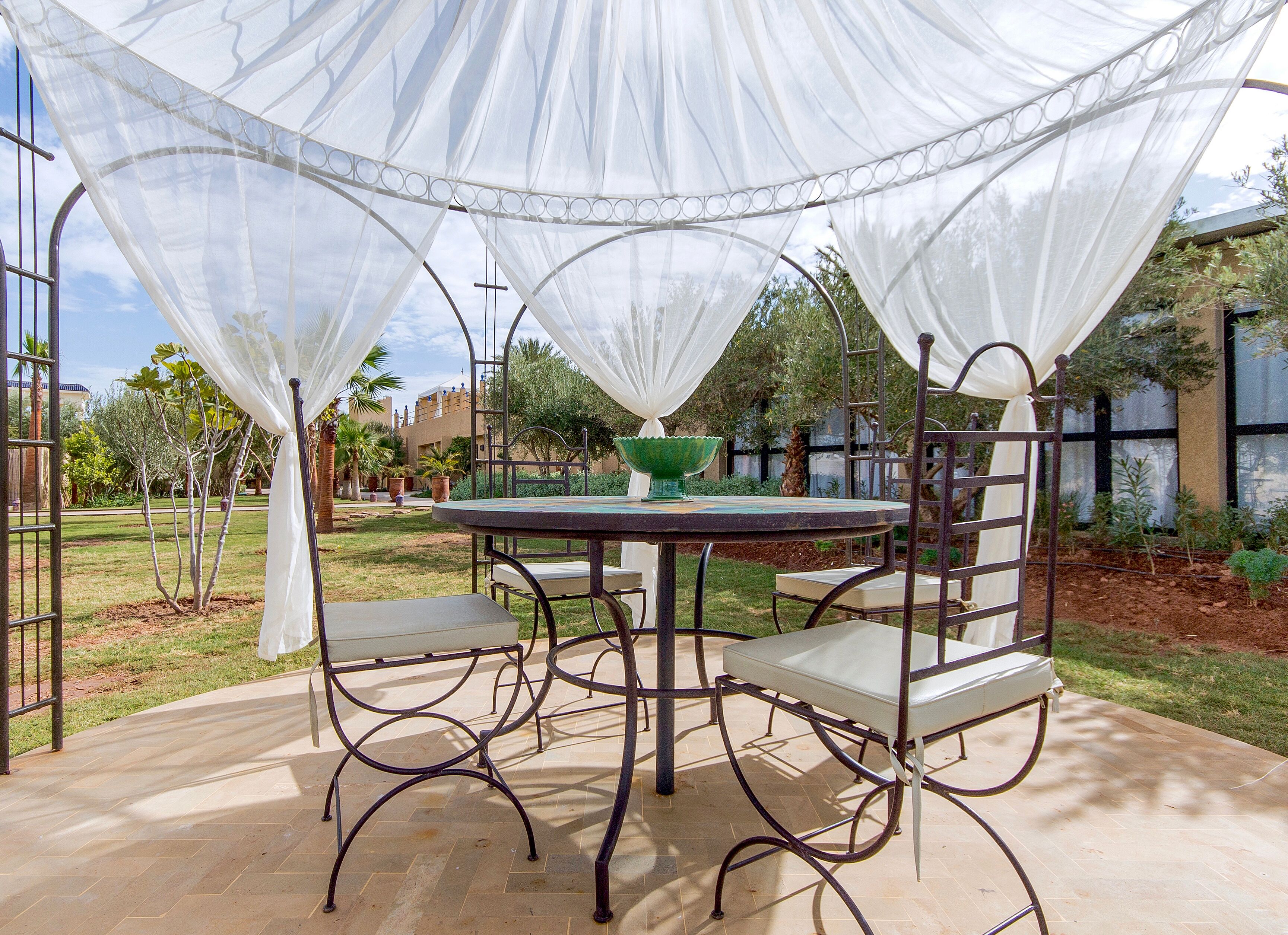 Un patio exterior con una mesa redonda, cuatro sillas y un tazón verde.