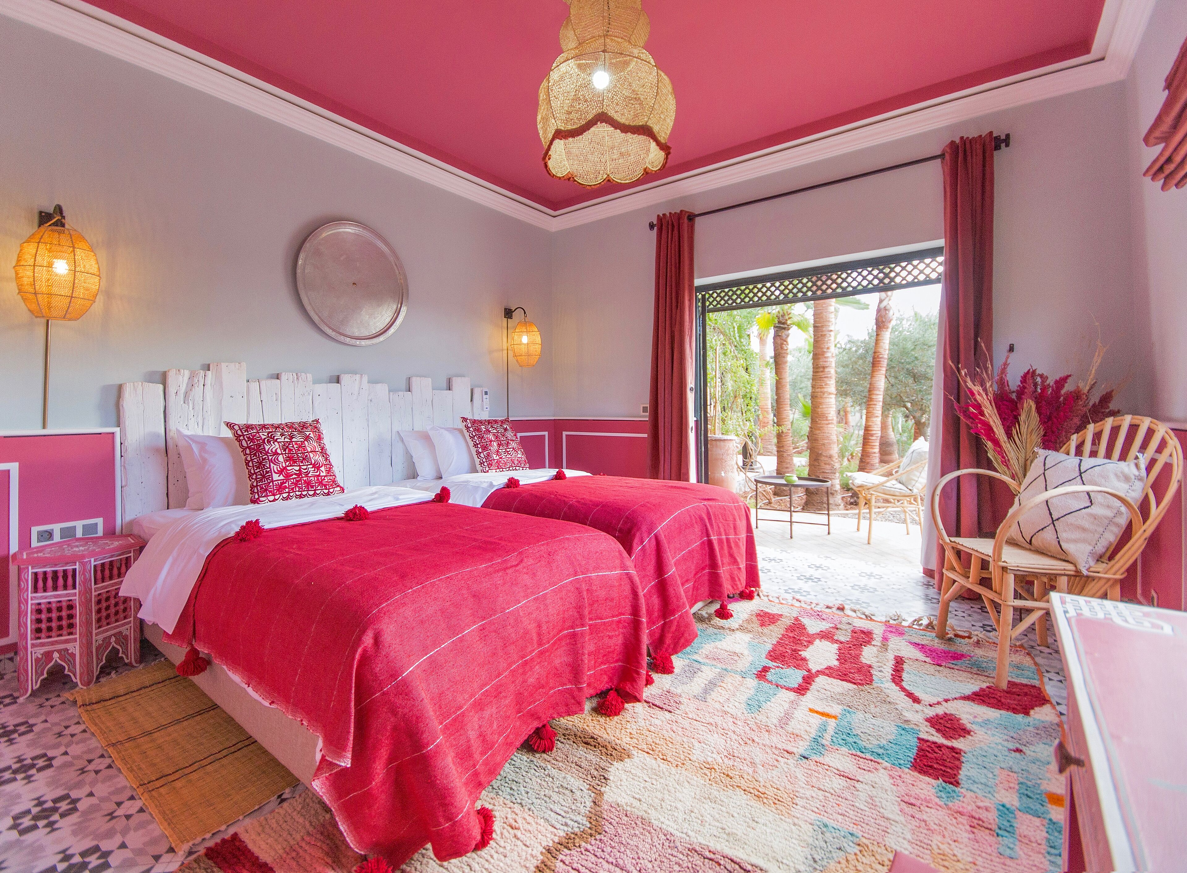 Une chambre avec deux lits, une grande fenêtre et un balcon.