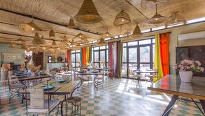 A spacious dining area with checkered flooring, multiple tables and chairs, and hanging woven light fixtures. - Maison Daouia (Marrakech)