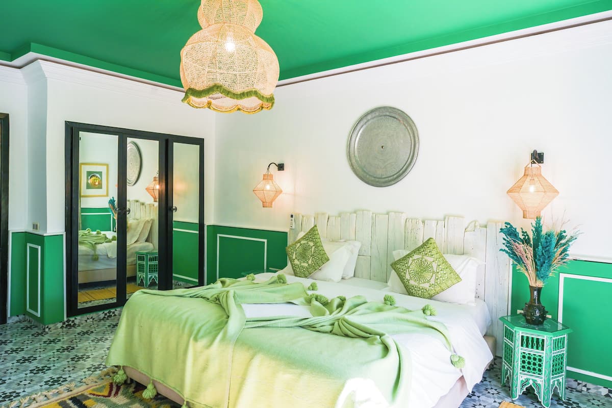 A room with a bed, a mirror, and a green and white color scheme.